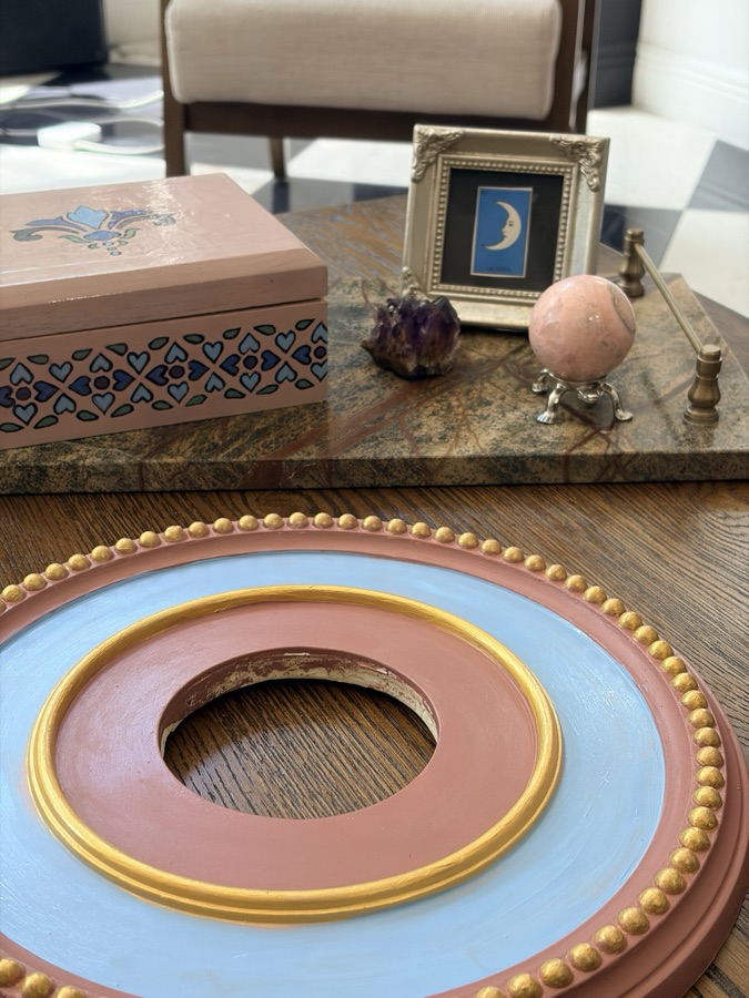 Close view of the medallion's hand-painted surface, gilded inner ring and center opening.